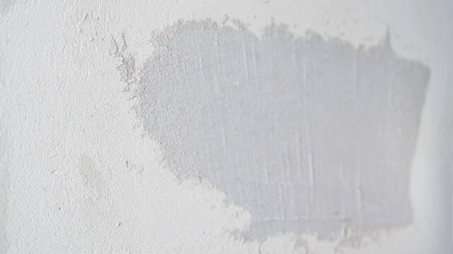 Applying putty to a plastered wall with a metal spatula producing a sharp squeaky sound, ASMR construction
