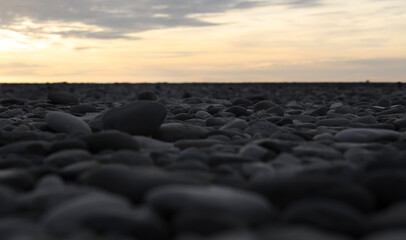 Obraz premium perspective view on washed gravel in gray, laid out on ground Grey rock gravel pebble gravel stone background Pebbles on beach in perspective Top view of round river stones floor. sunset sky Black sea