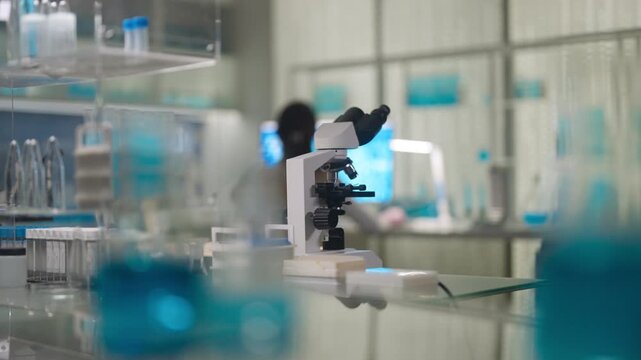Female scientist in protective gear working in a modern laboratory to test human DNA samples. Examining data on a computer. Selective focus on the equipment