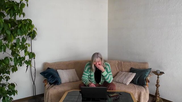 Senior woman having video call on sofa showing different emotions