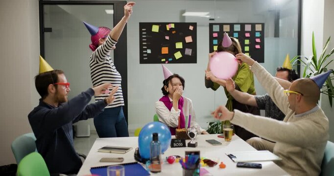 Business team celebrates with balloons and decorations in office meeting room during a casual gathering to enhance teamwork and camaraderie