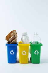 Sorting and recycling waste, colorful recycling bin with glass, paper, and plastic on white background. Containers for waste separation, promoting eco friendly living and environmental awareness.