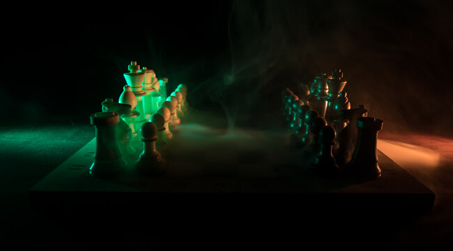 Chess board game concept of business ideas and competition. Chess figures on a dark background with smoke and fog.