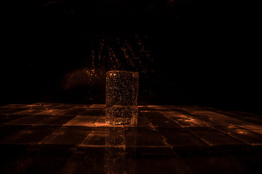 Crystal clear frosty textured natural ice block with cracks on black mirroring surface.