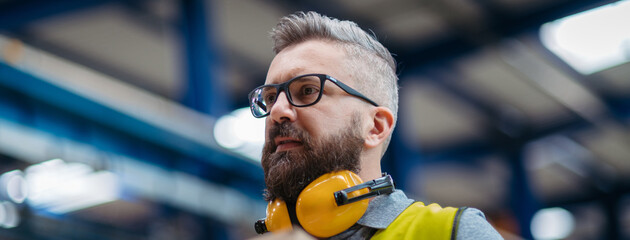 Warehouse or factory worker with protective earmuffs.