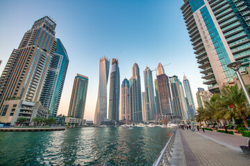 Naklejka premium Dubai Marina skyscrapers glowing at sunset with waterfront reflections in Dubai UAE