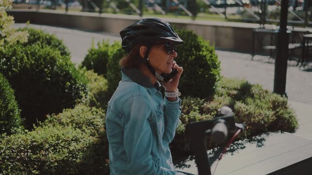 Active senior woman using an electric scooter in a city park. Modern micro-mobility solutions provide independence and eco-friendly transportation for all generations in the urban environment.