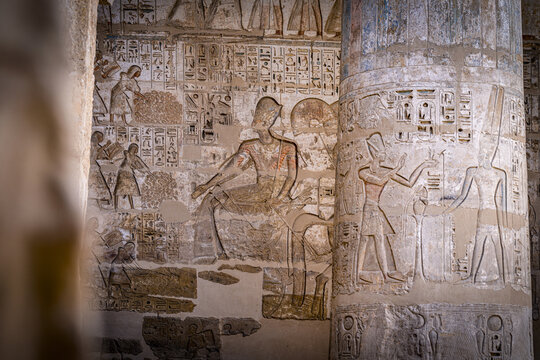 View of ancient hieroglyphs etched into weathered stone walls, telling tales of pharaohs and gods in muted ochre tones, Luxor, Luxor Governorate, Egypt.