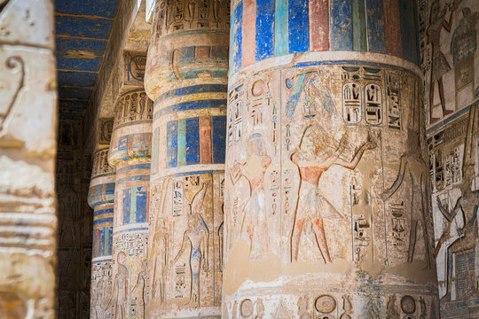 Intricately carved columns standing tall in the ancient Karnak Temple, their surfaces adorned with vibrant hieroglyphs, Luxor, Luxor Governorate, Egypt.