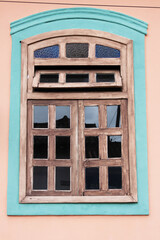 Obraz premium Weathered wooden window, multi-paned and arched, adorns a peach wall.