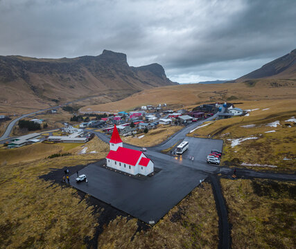 Aerial view of Reyniskirkja Church stands out with its vibrant red roof against the muted Icelandic landscape, creating a stunning contrast, Vik, Myrdalshreppur, Iceland.