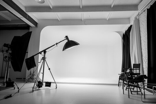Professional photo studio with white cyclorama wall and lighting equipment. Monochrome interior of creative workspace for photography and video production