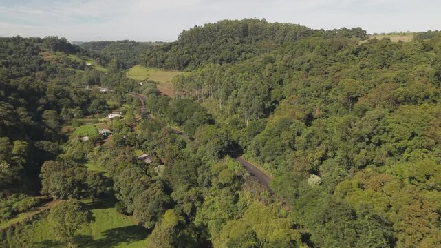 Estrada rural em meio a bosques e vale.