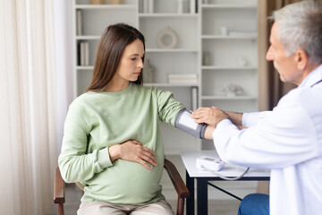 Obraz premium Doctor measuring pregnant womans blood pressure during prenatal checkup. Healthcare professional monitoring maternal health and pregnancy condition in clinic