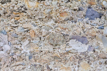 Obraz premium Close-up of an old, rustic stone wall. Irregular, multi-colored rocks and visible mortar form a rough, earthy texture. 