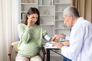 Obraz premium Pregnant woman experiencing dizziness while doctor checks blood pressure during prenatal consultation. Healthcare professional assessing maternal health symptoms