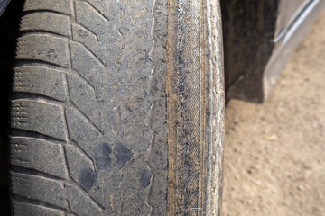 A person is wiping down the dirty wheel of a car to maintain its condition and prevent damage while parked outside