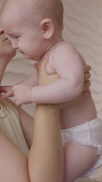 Mother soothes aggrieved infant. Calm mother tenderly comforts crying infant through gentle pats and caring touch and pacifier. Soft authentic light enhances loving connection