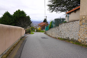 Quiet asphalt road in Thiers, France, with stone walls and scenic mountain valley view © Life Background