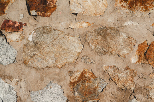 Textura de muro de piedra r&uacute;stico con mortero envejecido y tonos ocres, pared antigua en luz natural