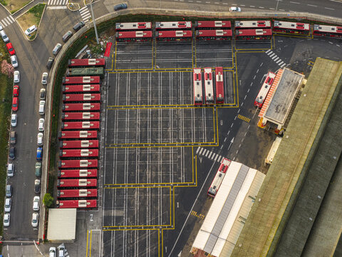Aerial view of a bus depot with orderly rows of red and white buses on asphalt, a testament to urban organization, Rome, Lazio, Italy.