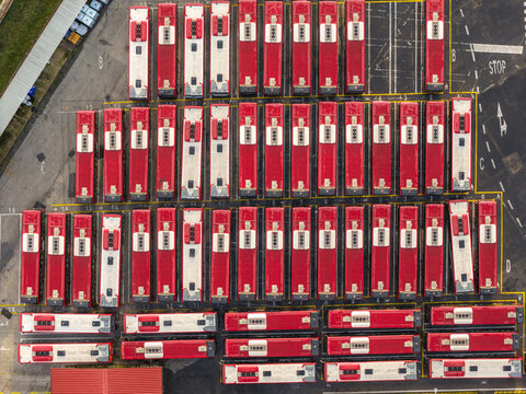 Aerial view of neatly arranged red and white buses parked in precise rows and columns, creating a striking geometric pattern from above, Rome, Lazio, Italy.