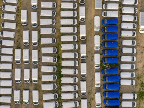 Aerial view of rows of white and blue vans parked in neat lines, creating a geometric pattern from above, Rome, Lazio, Italy.