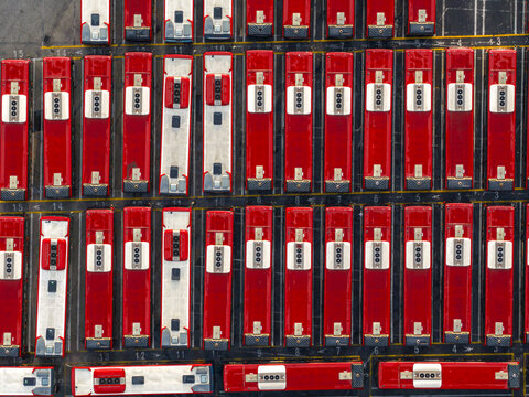 Aerial view of vivid red and white buses parked in precise rows, creating a striking geometric pattern from above, Rome, Lazio, Italy.