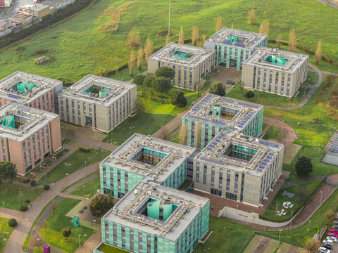 Aerial view of modern buildings with striking green accents and solar panels stand amidst manicured lawns, a testament to contemporary design, Rome, Lazio, Italy.