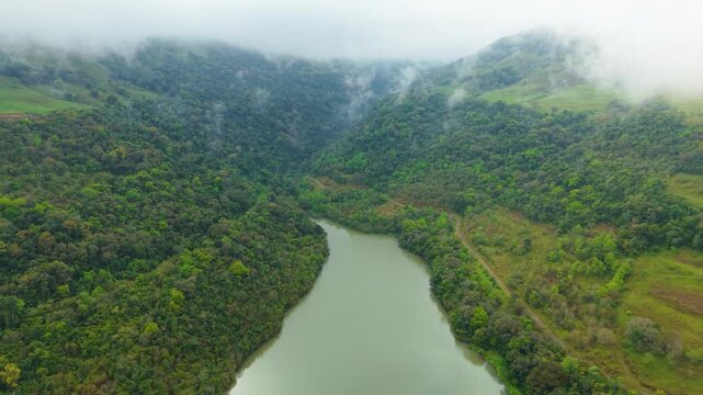 Lago verde entre montanhas, nuvens e florestas. Drone. 4K.