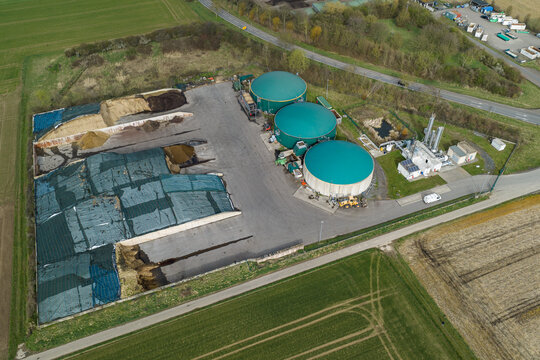 Aerial view of a biogas plant featuring green circular tanks contrasting with the earthy tones of adjacent fields, Gross-Umstadt, Hessen, Germany.