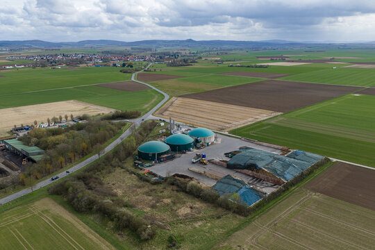 Aerial view of the Biogasanlage's verdant domes amidst the patchwork fields, contrasting with the village Semd distant silhouette, Gross-Umstadt, Hessen, Germany.