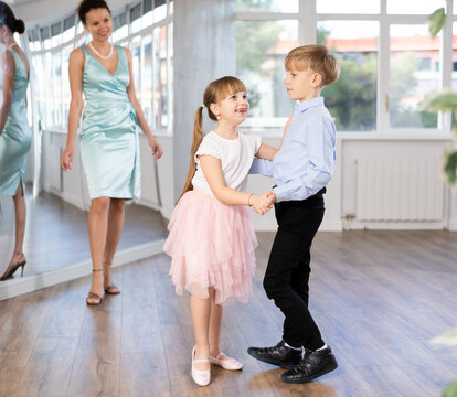 Couple of boy and girl kids twirling while taking waltz ballroom dancing lessons.