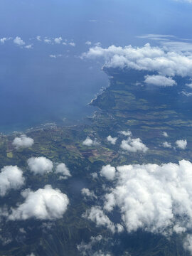 Aerial view of Maui Hawaii coastline featuring dramatic clouds, ocean, and island landscape. Scenic travel background with natural environment and geography.