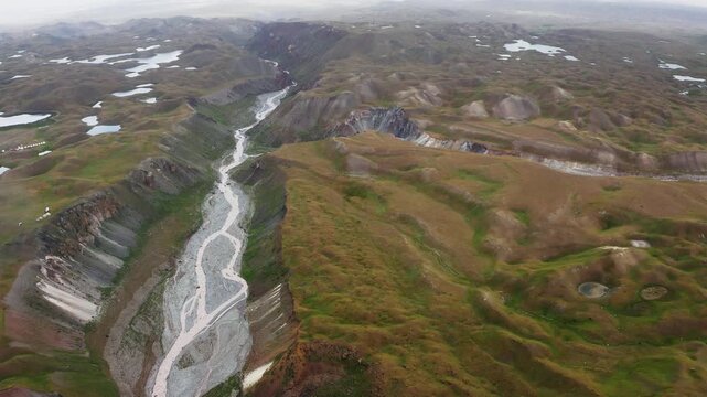 Flying drone 4K video over river canyon landscape during deep in Pamir mountains. Lenin peak climbing acclimatization route near 3600m Base Camp, Kyrgystan, Central Asia
