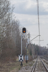 Sygnał kolejowy z czerwonym światłem przy torach, infrastruktura kolejowa i bezpieczeństwo ruchu, linia kolejowa na tle lasu. © Henryk Guziak