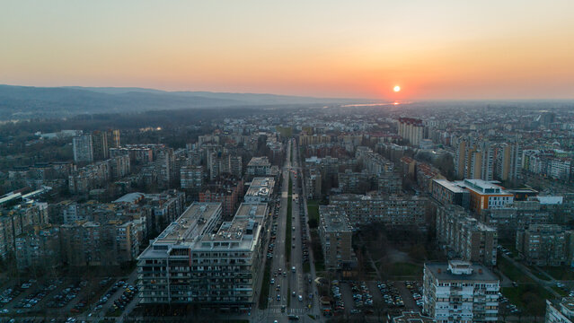 Aerial view of the cityscape bathed in the warm glow of the setting sun, buildings casting long shadows across the streets, Novi Sad, Vojvodina, Serbia.