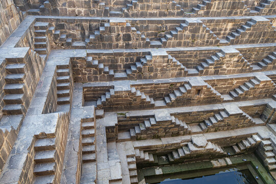 View of intricate, geometric steps descend into the ancient Chand Baori stepwell, a mesmerizing display of architectural heritage, Bandikui, Rajasthan, India.