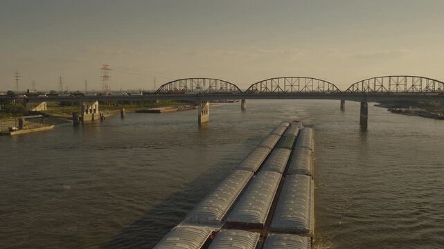 An aerial flyover of a barge on the Mississippi river at dusk near St. Louis, MO