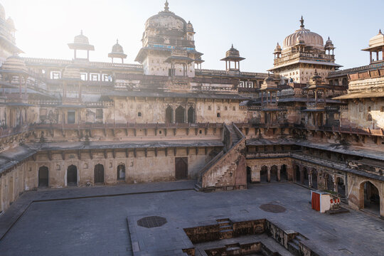 View of the weathered, multi-tiered Orchha Fort complex, with its ornate domes and intricate stonework, bathed in the soft glow of the Indian sun, Orchha, Madhya Pradesh, India.