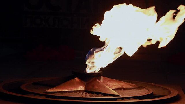 Close up of bright eternal flame burning on bronze star memorial