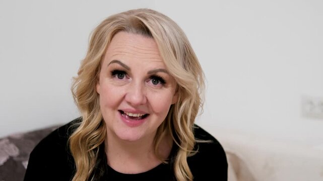 Mature European Woman Nods and Smiles, Affirming and Cheerful Expression, Blonde Hair, Light Makeup, Positive Gesture on White Wall Background