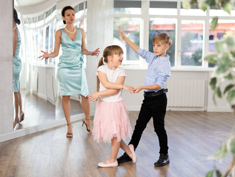 Couple of boy and girl kids twirling while taking waltz ballroom dancing lessons.