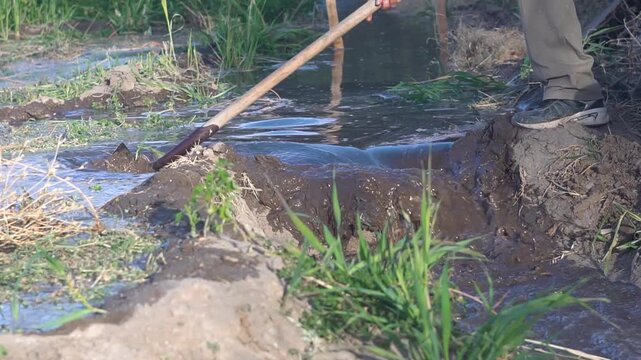 persona abre canal de riego con pala