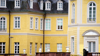 Bright yellow royal-style castle stands prominently with towers and ornate facade details. The warm colored walls contrast with the sky and surrounding greenery, giving the building a fairytale, regal © Василий Канин
