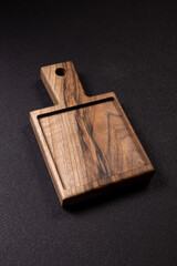 Fototapeta premium Walnut wooden serving board with handle on black background