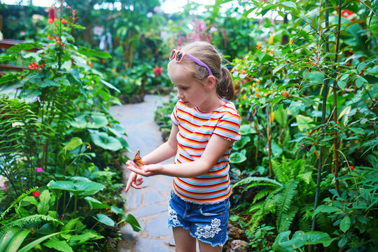 Little girl gently holding a monarch butterfly on her finger in a butterfly park in Icod de los Vinos, Tenerife, Canary Islands, Spain