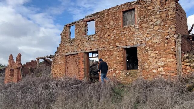 Hombre entrando a casa en ruinas en pueblo abandonado