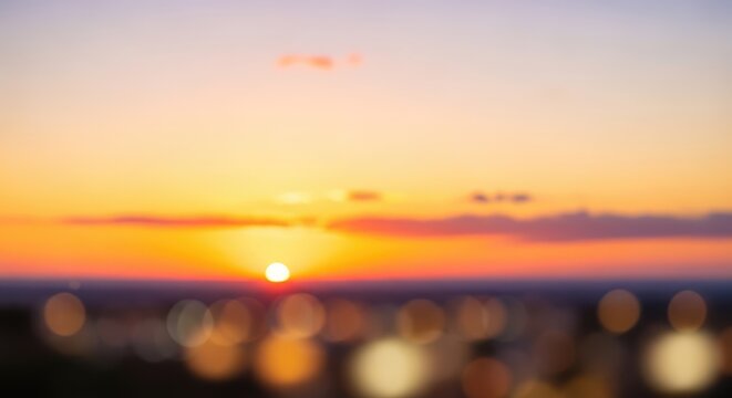 Blurred Sunset Over Cityscape with Golden Hour Sky and Bokeh Lights.
