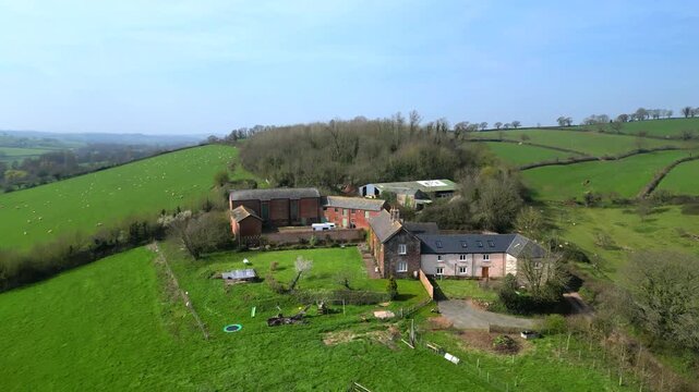Crediton, Devon, England: DRONE VIEWS: The drone flies over a farmhouse and farm buildings before revealing the countryside beyond. Crediton is located 7 miles north west of Exeter.